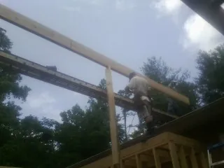 Carpenter setting a ridge beam over a new addition frame — Ice Dam Removal by Roofing Brothers in La Vernia