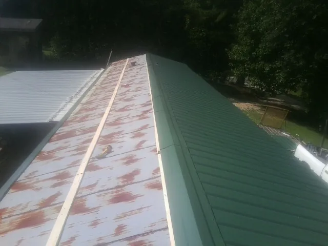 Old rusted panels beside newly installed green metal roofing — Wind Damage Roof Repair by Roofing Brothers in La Vernia