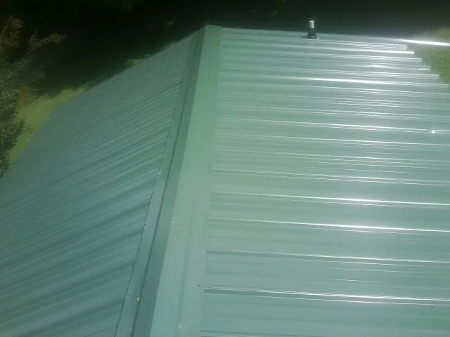 New green metal panels meeting at the ridge of a roof — Flat Roof Repair work by our crew in La Vernia