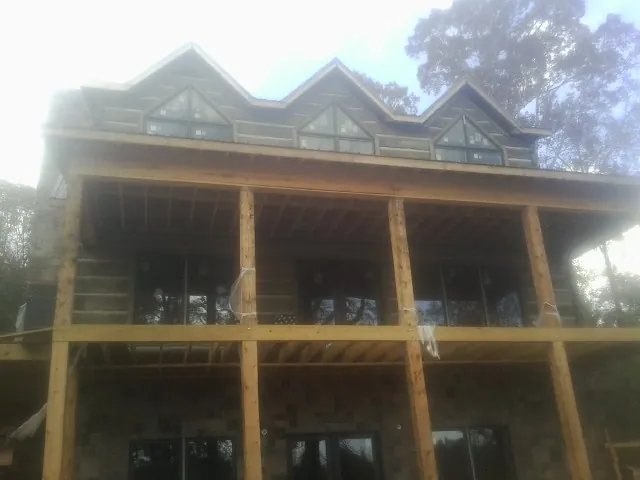 Dormers and porch framing on a large log home under construction — Roof Coating work by our crew in La Vernia