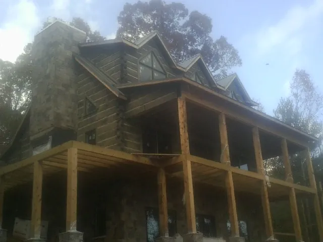 Stone chimney and dormers on a large log home with a timber porch in La Vernia