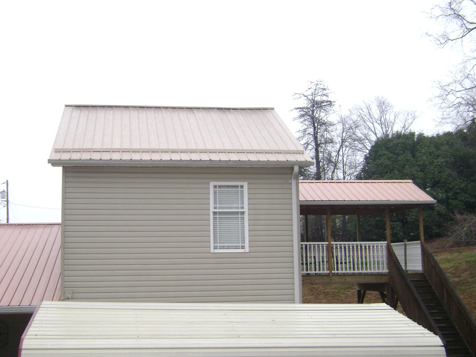 Tan metal roofs on a two story addition and attached porch, from a Roof Replacement job in La Vernia